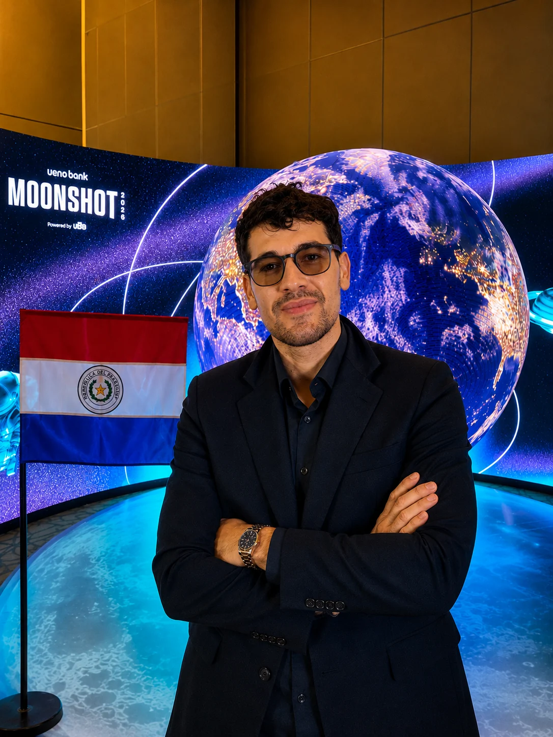 Diego Laconich con traje oscuro junto a la bandera de Paraguay en un evento tecnológico